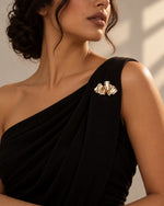 Tie Shop Gold Pleated Ribbon Brooch on black dress. بروش نسائي من تاي شوب بتصميم طيات ذهبية، إكسسوار أنيق للحجاب والملابس.