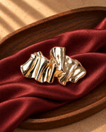Tie Shop Gold Pleated Ribbon Brooch on red silk. بروش نسائي من تاي شوب مموج باللون الذهبي، إكسسوار أنيق للحجاب والملابس.
