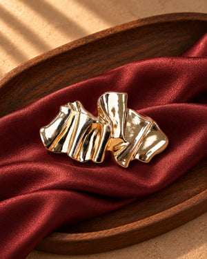 Tie Shop Gold Pleated Ribbon Brooch on red silk. بروش نسائي من تاي شوب مموج باللون الذهبي، إكسسوار أنيق للحجاب والملابس.