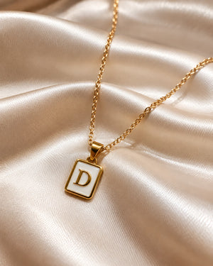 Tie Shop D Initial Necklace gold mother of pearl pendant display. سلاسل نسائية من تاى شوب دي إنيشال نيكليس، قلادة ذهبية بدلاية مستطيلة بحرف D وخلفية صدف عرق اللؤلؤ، مجوهرات وإكسسوارات أنيقة.