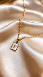 Tie Shop S Initial Necklace gold mother of pearl pendant display. سلاسل نسائية من تاى شوب اس إنيشال نيكليس، قلادة ذهبية بدلاية مستطيلة بحرف S وخلفية صدف عرق اللؤلؤ، مجوهرات وإكسسوارات أنيقة.
