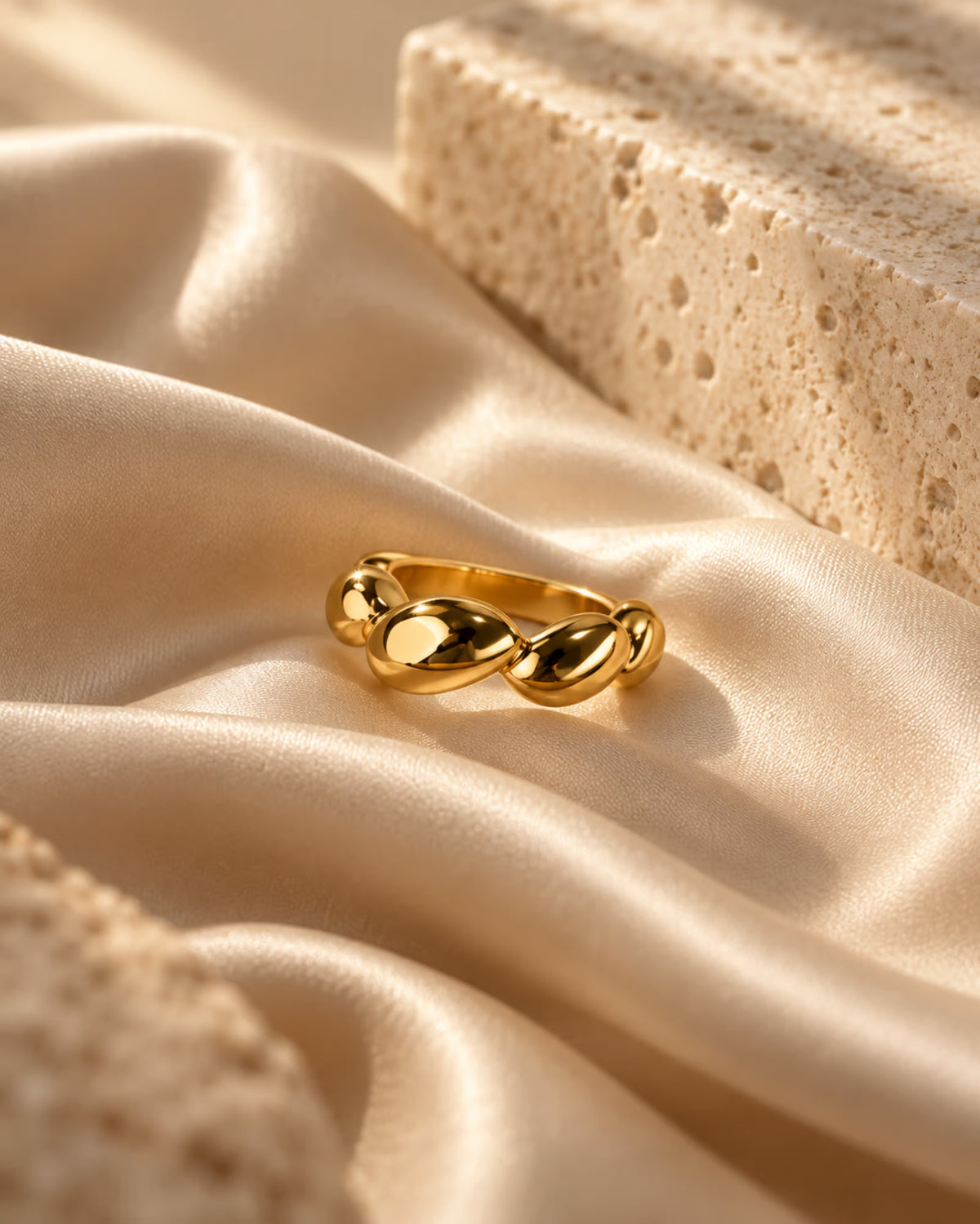 Tie Shop gold chunky croissant dome ring on smooth silk background. خواتم نسائية من تاي شوب خاتم كرواسون ذهبي بارز بتصميم كرويسانت دوم سميك، مجوهرات وإكسسوارات أنيقة.