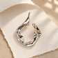 Detailed view of Tie Shop Abstract Fluid Silver Brooch, an elegant statement accessory for evening wear. عرض تفصيلي لـ بروش تجريدي انسيابي فضي من تاي شوب، اكسسوار أنيق يضفي لمسة راقية على إطلالات السهرة.