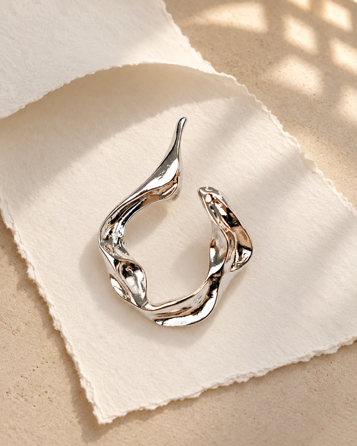 Detailed view of Tie Shop Abstract Fluid Silver Brooch, an elegant statement accessory for evening wear. عرض تفصيلي لـ بروش تجريدي انسيابي فضي من تاي شوب، اكسسوار أنيق يضفي لمسة راقية على إطلالات السهرة.