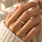 Tie Shop gold ring with baguette and round cz crystals on model hand. خواتم نسائية من تاي شوب خاتم ذهبي مرصع بأحجار الزركون المستطيلة والدائرية، مجوهرات وإكسسوارات أنيقة.