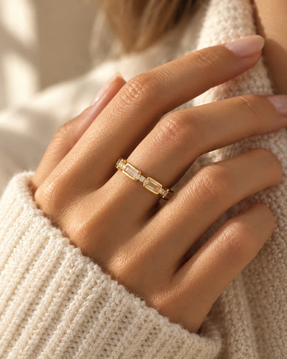 Tie Shop gold ring with baguette and round cz crystals on model hand. خواتم نسائية من تاي شوب خاتم ذهبي مرصع بأحجار الزركون المستطيلة والدائرية، مجوهرات وإكسسوارات أنيقة.