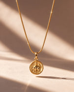 Tie Shop gold Taurus zodiac coin necklace on aesthetic shadow background. سلاسل نسائية من تاى شوب قلادة ذهبية بدلاية دائرية لنقشة برج الثور، مجوهرات وإكسسوارات أنيقة.