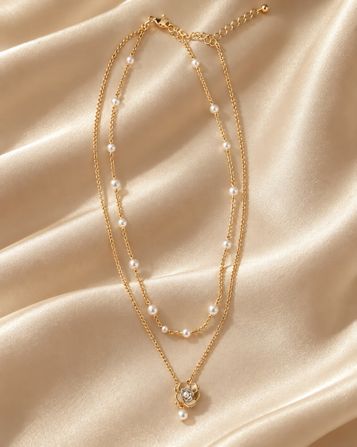 Tie Shop Flora Layered Pearl Necklace double strand gold chain with flower pendant display. سلاسل نسائية من تاى شوب فلورا لايرد بيرل نيكليس، سلسلة ذهبية مزدوجة الطبقات مرصعة باللؤلؤ ودلاية وردة أنيقة، مجوهرات وإكسسوارات أنيقة.