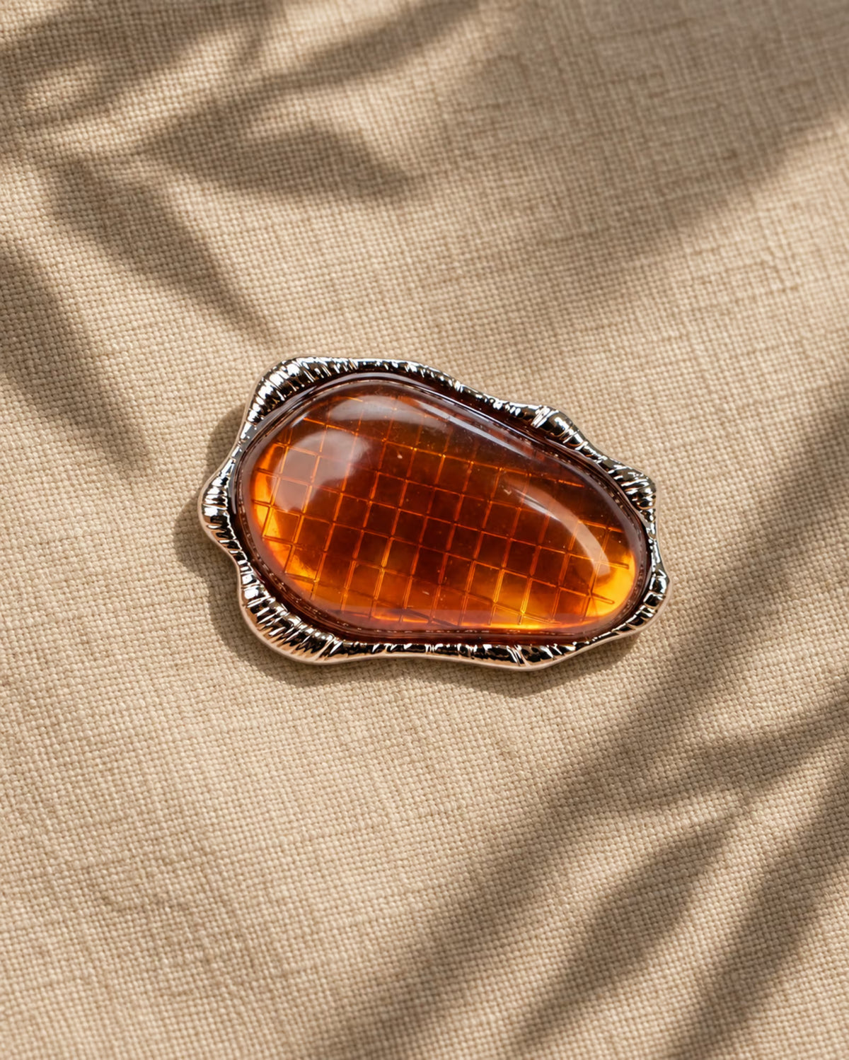 Detailed shot of Tie Shop Amber Stone Metallic Brooch, a statement accessory designed for dresses, abayas, and hijabs. عرض تفصيلي لـ بروش بحجر عنبري إطار معدني من تاي شوب، اكسسوار أنيق ومميز لتزيين الفساتين والعبايات والحجاب.