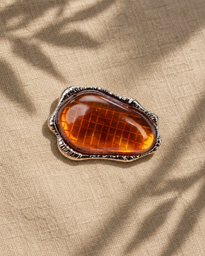 Detailed shot of Tie Shop Amber Stone Metallic Brooch, a statement accessory designed for dresses, abayas, and hijabs. عرض تفصيلي لـ بروش بحجر عنبري إطار معدني من تاي شوب، اكسسوار أنيق ومميز لتزيين الفساتين والعبايات والحجاب.