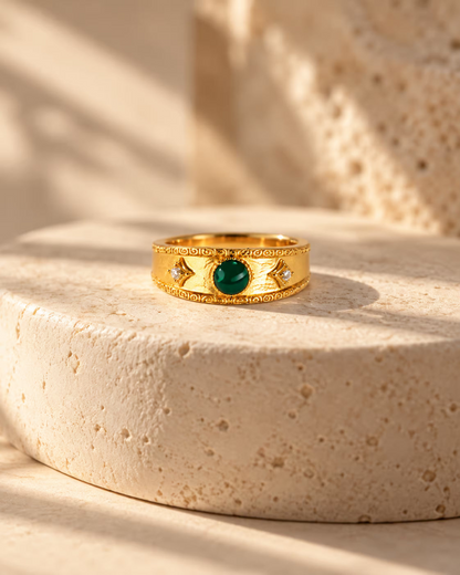 Tie Shop Royal Rings gold band with emerald green stone and cz accents on stone display. خواتم نسائية من تاى شوب رويال رينجز، خاتم ذهبي عريض منقوش بحجر أخضر ملكي وفصوص زركون، مجوهرات وإكسسوارات أنيقة.