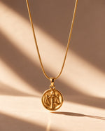 Tie Shop Libra Necklace gold zodiac coin pendant display. سلاسل نسائية من تاى شوب ليبرا نيكليس، قلادة ذهبية بدلاية دائرية لنقشة برج الميزان، مجوهرات وإكسسوارات أنيقة.