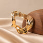 Close-up of Tie Shop Gold Organic Curved Ring Brooch on satin. بروش نسائي من تاي شوب بإطار عصري مموج، إكسسوار أنيق للحجاب والملابس.