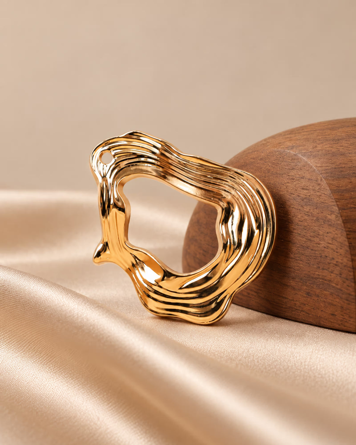 Close-up of Tie Shop Gold Organic Curved Ring Brooch on satin. بروش نسائي من تاي شوب بإطار عصري مموج، إكسسوار أنيق للحجاب والملابس.