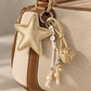 Tie Shop Beige Gold Leather Star Bag Charm on canvas purse. تعليقة حقيبة نسائية من تاي شوب بنجمة ذهبية وخرز، إكسسوار أنيق للشنط.