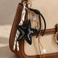 Tie Shop Black Snake Texture Star Bag Charm. تعليقة شنطة نسائية من تاي شوب بنجمة سوداء مزخرفة وأشرطة محبوكة، إكسسوار أنيق للحقائب.