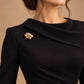 Tie Shop Gold Interlocking Curved Brooch on black dress. بروش نسائي من تاي شوب بتصميم ذهبي متداخل، إكسسوار أنيق للحجاب والملابس.