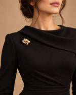 Tie Shop Gold Interlocking Curved Brooch on black dress. بروش نسائي من تاي شوب بتصميم ذهبي متداخل، إكسسوار أنيق للحجاب والملابس.