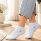A person wearing light blue ankle socks with a small embroidered cat and red heart design, paired with light blue jeans in a bright indoor setting.