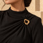 Tie Shop Gold Organic Curved Ring Brooch on black dress. بروش نسائي من تاي شوب بتصميم حلقة ذهبية مفرغة ومموجة، إكسسوار أنيق للحجاب والملابس.