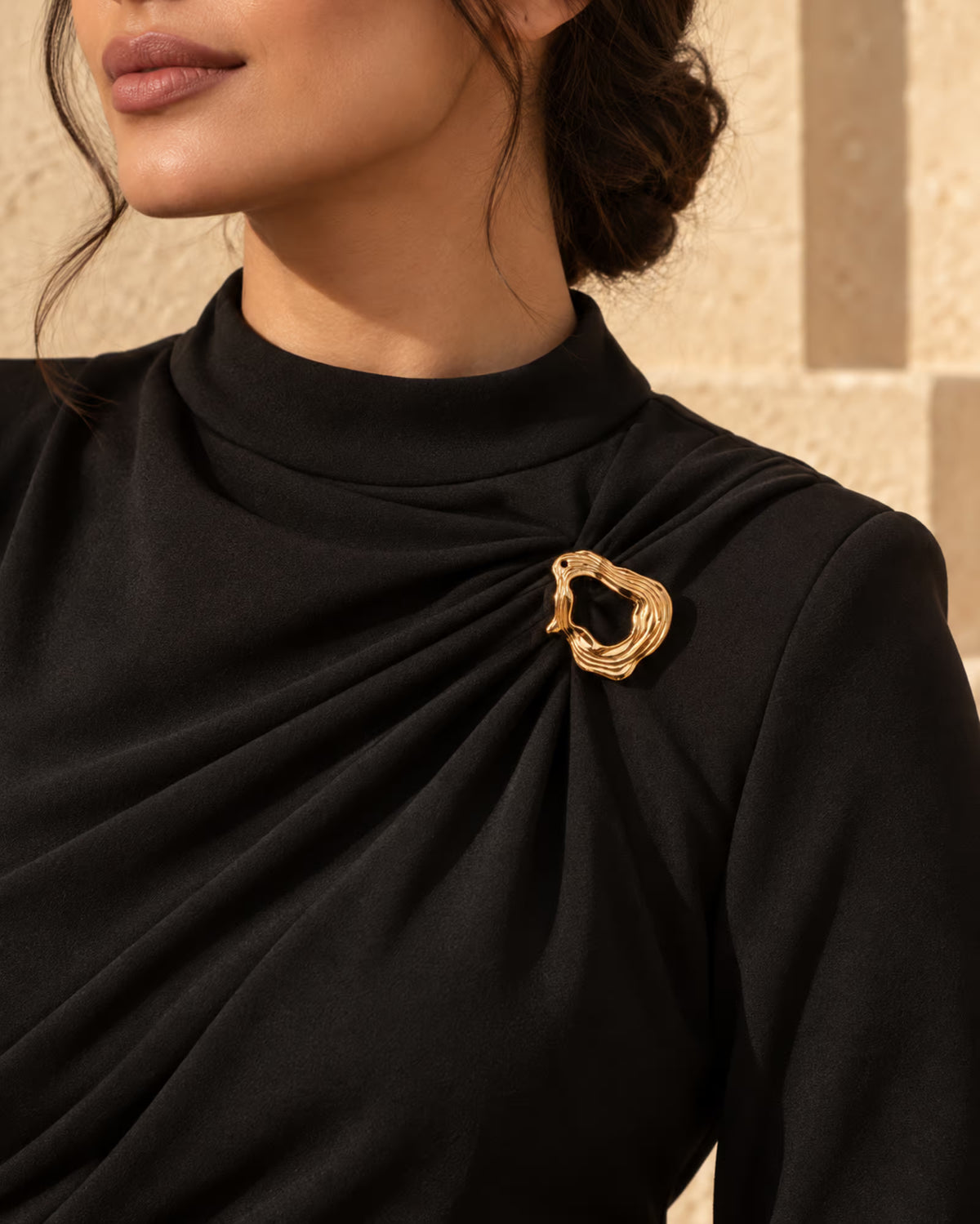 Tie Shop Gold Organic Curved Ring Brooch on black dress. بروش نسائي من تاي شوب بتصميم حلقة ذهبية مفرغة ومموجة، إكسسوار أنيق للحجاب والملابس.