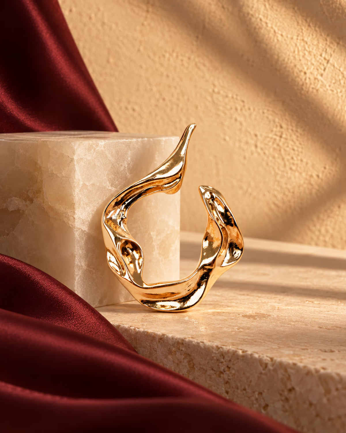 Close-up of Tie Shop Abstract Fluid Gold Brooch, a luxury metallic accessory for abayas, dresses, and hijabs. صورة مقربة لـ بروش تجريدي انسيابي ذهبي من تاي شوب، اكسسوار معدني فاخر للعبايات والفساتين والحجاب.