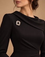 Tie Shop Silver Interwoven Knot Brooch on black dress. بروش نسائي من تاي شوب بتصميم فضي حلزوني متداخل، إكسسوار أنيق للحجاب والملابس.