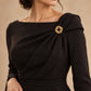 Tie Shop Gold Interlocking Curved Ring Brooch on black dress. بروش نسائي من تاي شوب بتصميم دوائر ذهبية متداخلة محززة، إكسسوار أنيق للحجاب والملابس.