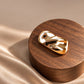 Tie Shop Gold Wave Bar Brooch on wooden pedestal. بروش نسائي من تاي شوب بلمسة ذهبية مصقولة ومطعجة، إكسسوار أنيق للحجاب والملابس.