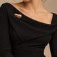 Tie Shop Smooth Gold Bean Brooch on black dress. بروش نسائي من تاي شوب بتصميم حبة ذهبية انسيابية، إكسسوار أنيق للحجاب والملابس.