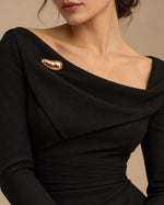 Tie Shop Smooth Gold Bean Brooch on black dress. بروش نسائي من تاي شوب بتصميم حبة ذهبية انسيابية، إكسسوار أنيق للحجاب والملابس.
