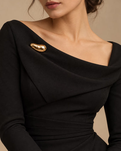 Tie Shop Smooth Gold Bean Brooch on black dress. بروش نسائي من تاي شوب بتصميم حبة ذهبية انسيابية، إكسسوار أنيق للحجاب والملابس.