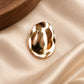 Tie Shop Gold Hammered Oval Brooch on ivory silk. بروش نسائي من تاي شوب بلمسة ذهبية متموجة، إكسسوار أنيق للحجاب والملابس.