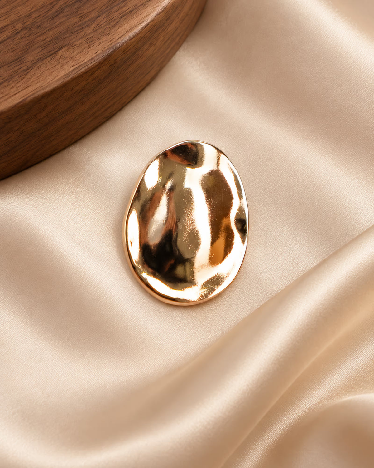 Tie Shop Gold Hammered Oval Brooch on ivory silk. بروش نسائي من تاي شوب بلمسة ذهبية متموجة، إكسسوار أنيق للحجاب والملابس.