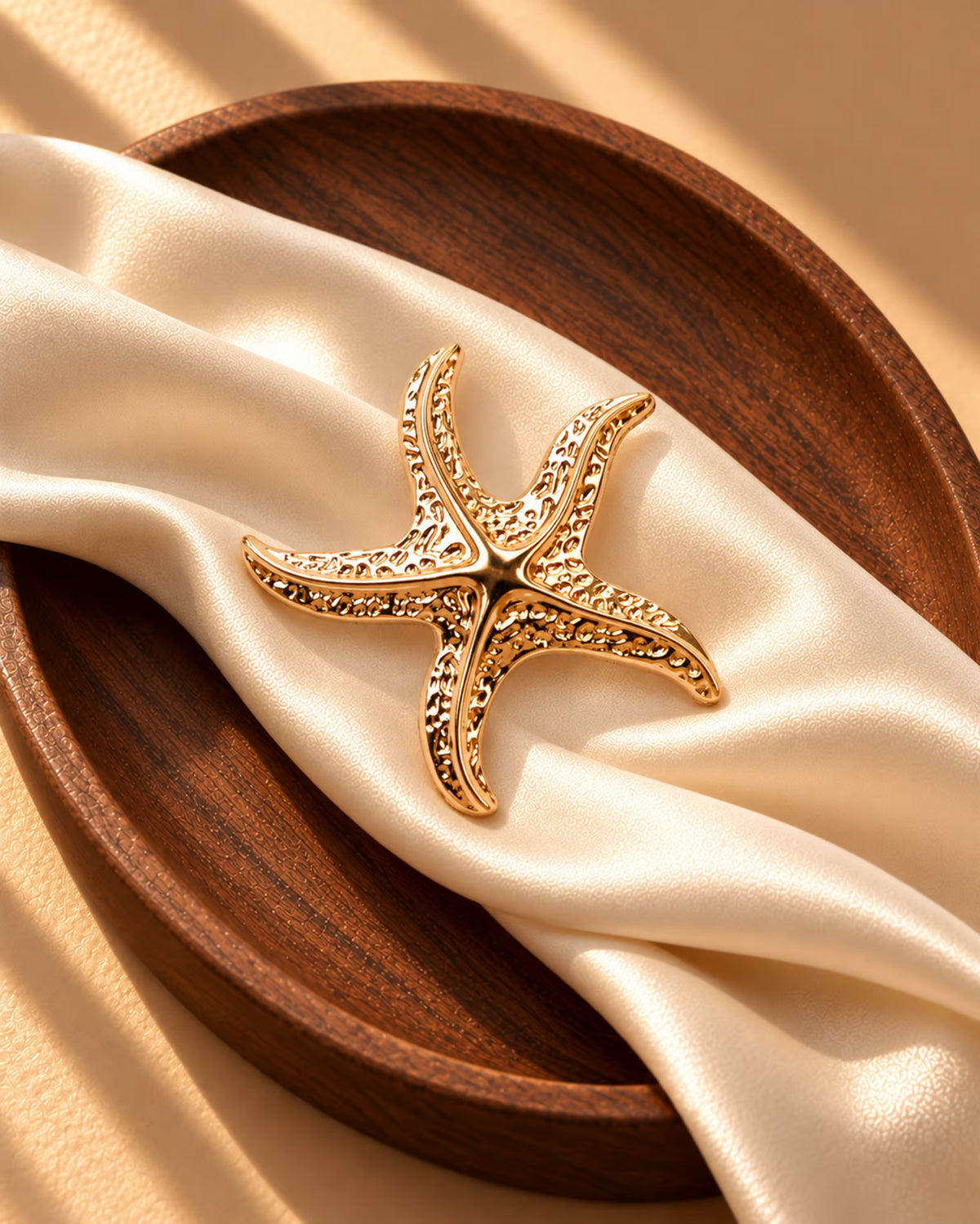 Tie Shop Gold Starfish Brooch on wooden pedestal. بروش نسائي من تاي شوب بتفاصيل محفورة باللون الذهبي، إكسسوار أنيق للحجاب والملابس.