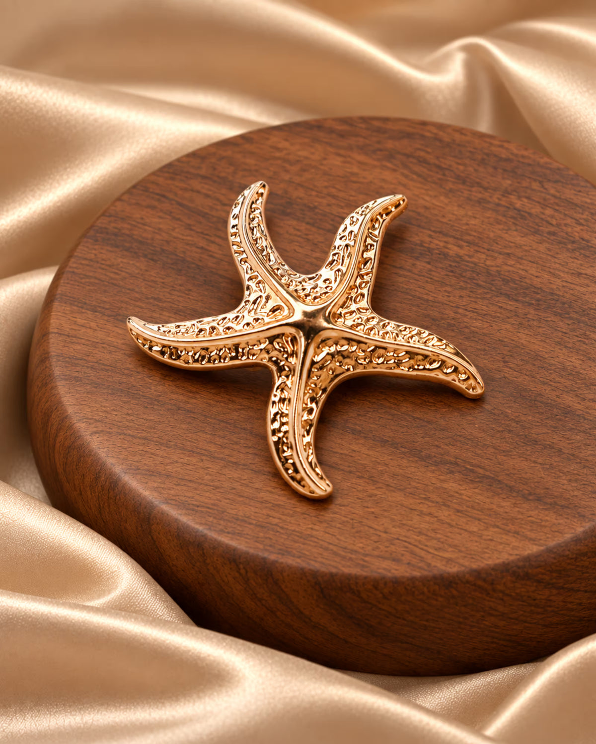Tie Shop Gold Starfish Brooch on champagne satin. بروش نسائي من تاي شوب بلمسة ذهبية فاخرة، إكسسوار أنيق للحجاب والملابس.