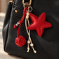 Tie Shop Red Leather Star Bag Charm on black handbag. تعليقة حقيبة نسائية من تاي شوب بنجمة جلد حمراء وخرز، إكسسوار أنيق للشنط.