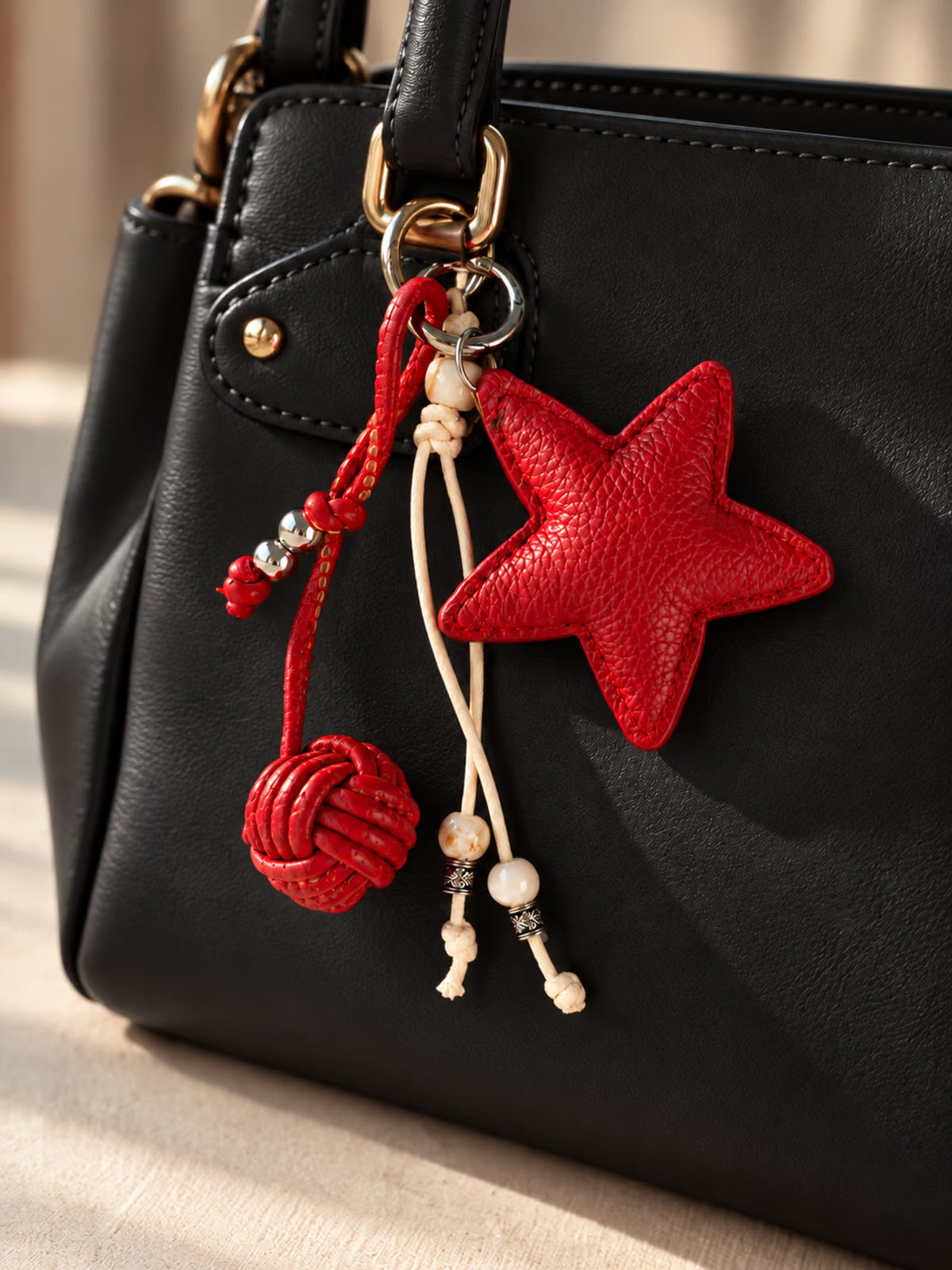 Tie Shop Red Leather Star Bag Charm on black handbag. تعليقة حقيبة نسائية من تاي شوب بنجمة جلد حمراء وخرز، إكسسوار أنيق للشنط.