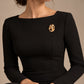 Tie Shop Gold Hammered Oval Brooch on black dress. بروش نسائي من تاي شوب بتصميم بيضاوي ذهبي مطروق، إكسسوار أنيق للحجاب والملابس.