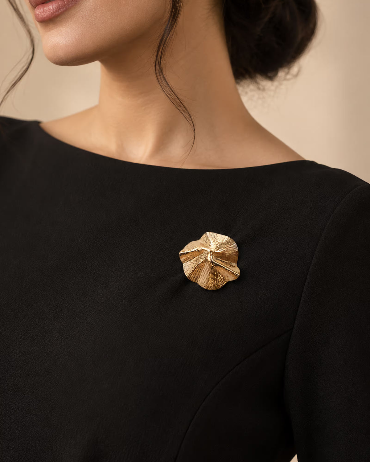 Model wearing a black formal dress adorned with the Sculptural Shell Gold Brooch from Tie Shop on the chest. موديل ترتدي فستان سهرة أسود مزين بـ بروش ذهبي بتصميم صدفة تجريدية من تاي شوب على الصدر للمناسبات.