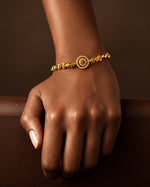 Tie Shop Classic Bracelet gold beaded with ruby cz medallion on model wrist. أساور نسائية من تاي شوب كلاسيك براسليت كرات ذهبية مع قرص مرصع بحجر أحمر، مجوهرات وإكسسوارات أنيقة.