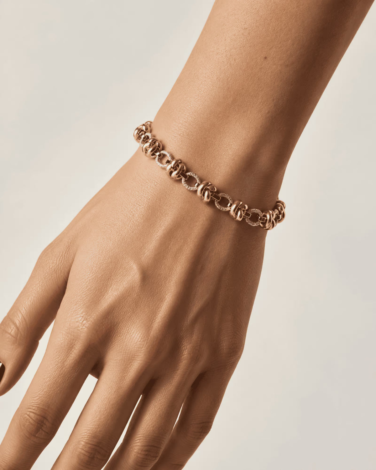 Tie Shop Stylish Bracelet gold double ring link chain with textured details on model wrist. أساور نسائية من تاي شوب ستايلش براسليت بتصميم سلسلة ذهبية بحلقات مزدوجة ومحززة، مجوهرات وإكسسوارات أنيقة.