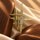 Detail shot of Tie Shop Gold Sparkling Star Crystal Brooch displayed between wooden props on silk fabric. صورة دقيقة لـ بروش النجوم الذهبي المرصع بالكريستال من تاي شوب بين عناصر خشبية وقماش حريري. بروش Zia النسائي، إكسسوار أنيق للحجاب والملابس
