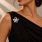 Side view of a model wearing Tie Shop Silver Calla Lily Pearl Flower Brooch on a black evening gown. لقطة جانبية لموديل ترتدي بروش وردة اللؤلؤ الفضي من تاي شوب على فستان سهرة أسود. بروش  النسائي، إكسسوار أنيق للحجاب والملابس 