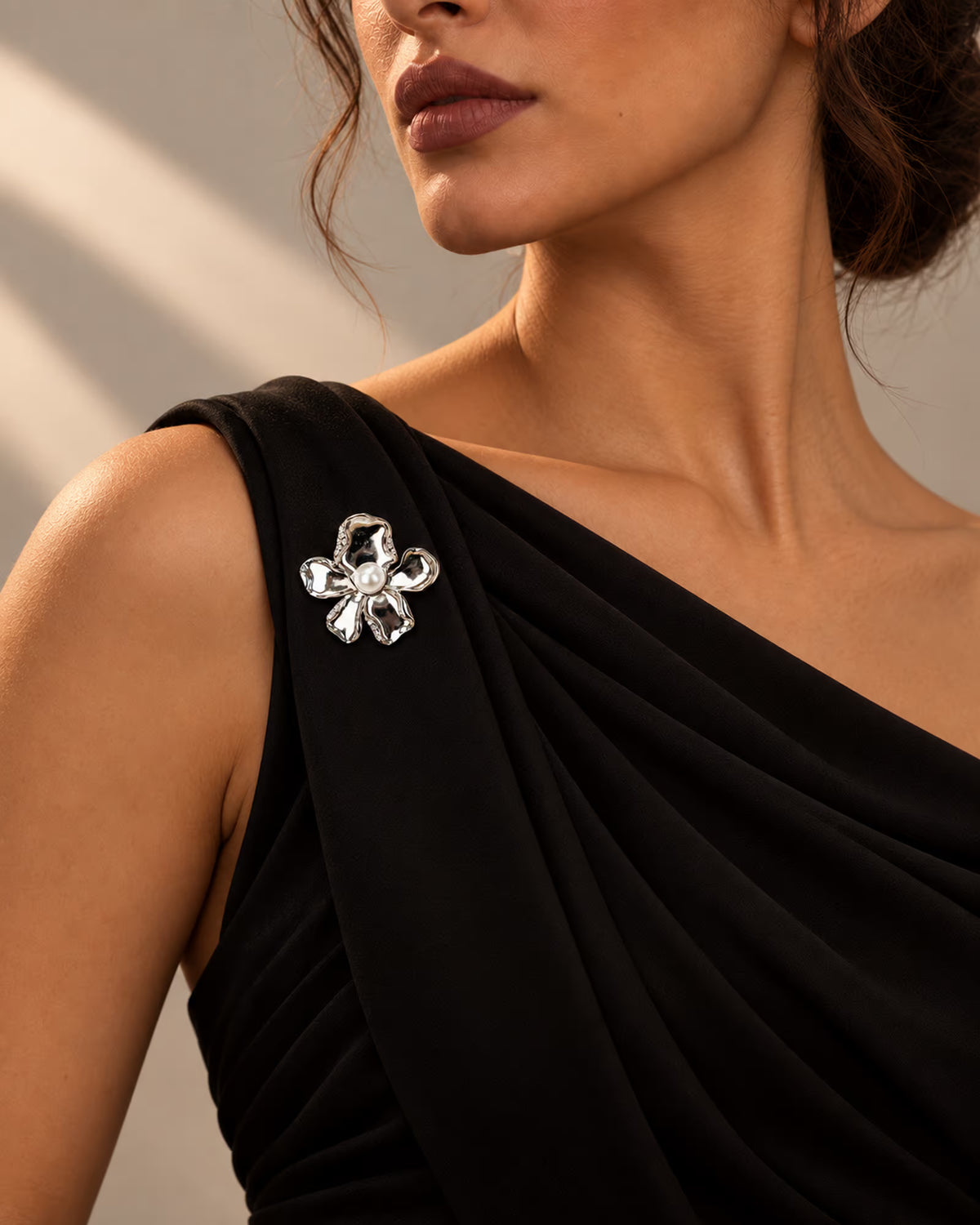 Side view of a model wearing Tie Shop Silver Calla Lily Pearl Flower Brooch on a black evening gown. لقطة جانبية لموديل ترتدي بروش وردة اللؤلؤ الفضي من تاي شوب على فستان سهرة أسود. بروش  النسائي، إكسسوار أنيق للحجاب والملابس 