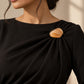 Model wearing a formal black dress styled with Tie Shop Yellow Amber Stone Gold Brooch, a luxury brooch accessory for women's hijab and outfits. موديل ترتدي فستان أسود أنيق مزين بـ بروش نسائي من تاي شوب بتصميم حجر العقيق الأصفر العسلي بإطار ذهبي، إكسسوار أنيق للحجاب والملابس.
