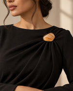 Model wearing a formal black dress styled with Tie Shop Yellow Amber Stone Gold Brooch, a luxury brooch accessory for women's hijab and outfits. موديل ترتدي فستان أسود أنيق مزين بـ بروش نسائي من تاي شوب بتصميم حجر العقيق الأصفر العسلي بإطار ذهبي، إكسسوار أنيق للحجاب والملابس.