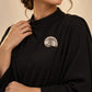 Model wearing an elegant black dress styled with Tie Shop Silver Polished Spiral Sea Shell Brooch, a chic metallic accessory for abayas and gowns. موديل ترتدي ملابس أنيقة باللون الأسود مزينة بـ بروش القوقعة المصقولة الفضي من تاي شوب،  اكسسوار راقي للعبايات والفساتين والطرح و الملابس