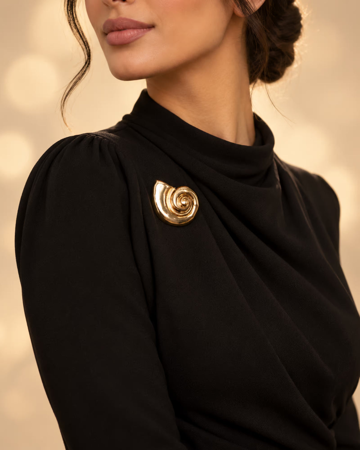 Model wearing a black formal dress decorated with Tie Shop Gold Polished Spiral Sea Shell Brooch on the chest, an elegant statement accessory. موديل ترتدي فستان أسود أنيق مزين بـ بروش القوقعة المصقولة الذهبي من تاي شوب على الصدر، لمسة فاخرة للملابس . بروش للحجاب والملابس .اكتشفي أناقة بروش Zia مع الحجاب والملابس
