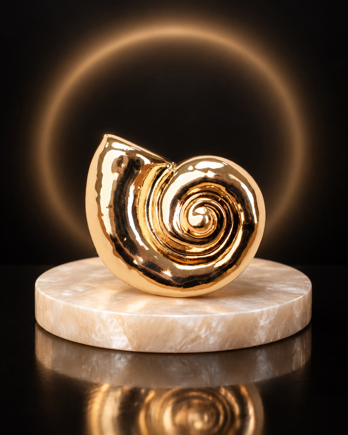 Close-up of Tie Shop Gold Polished Spiral Sea Shell Brooch on a round marble display stand with glowing background, a luxury fashion brooch. صورة مقربة لـ بروش القوقعة المصقولة الذهبي من تاي شوب على قاعدة رخامية دائرية مع خلفية مضيئة، بروش فاخر وعصري. بروش Zia لإضافة لمسة مميزة لإطلالتك اليومية